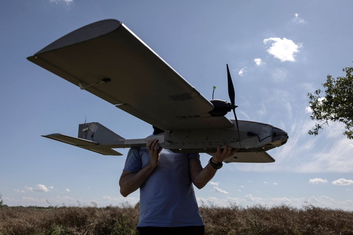 Güneşli, parçalı bulutlu bir gökyüzü altında açık havada büyük bir drone tutan kişi.