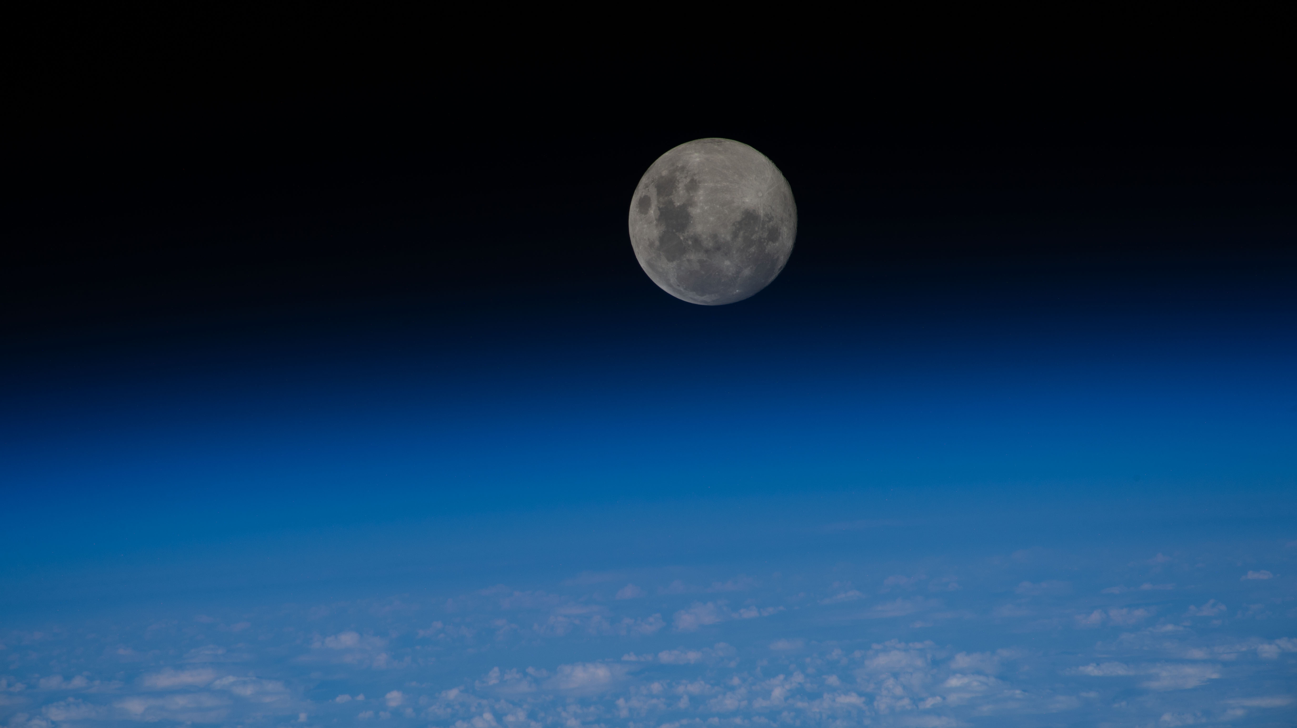 The last full moon of 2023, the "Cold Moon," sits just above the blue glow of Earth\